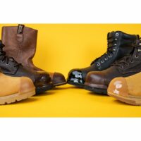 Assortment of work boots against a yellow backdrop, showcasing various stages of wear and TUFF TOE reinforcement on the toe caps