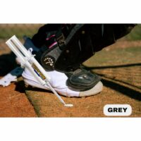Close-up of a baseball player's shoe with protective gear, next to a TUFF TOE adhesive applicator on a sunny baseball field