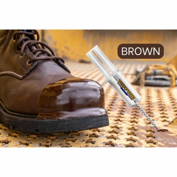 Close-up of a brown leather boot's toe cap with applied TUFF TOE protection, next to a TUFF TOE adhesive tube emphasizing the color 'BROWN', set against a rusty industrial background.