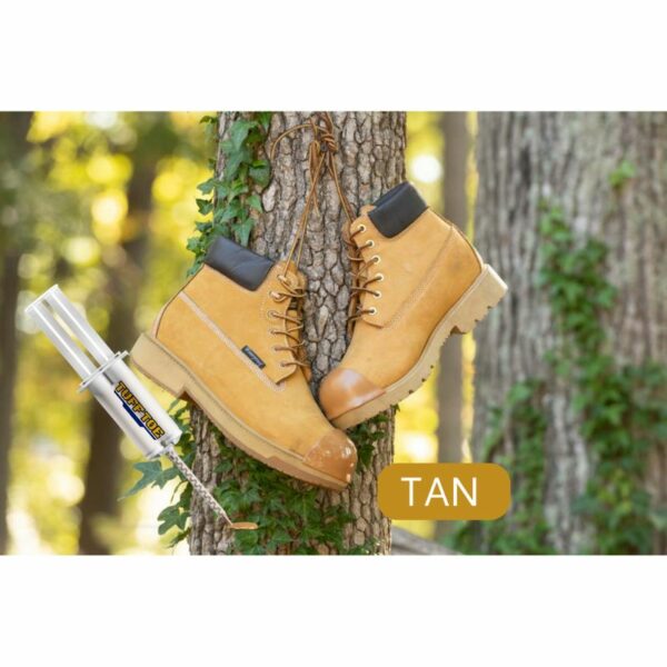 Tan work boots hanging from a tree trunk with a TUFF TOE adhesive tube nearby, set against a blurred forest background.